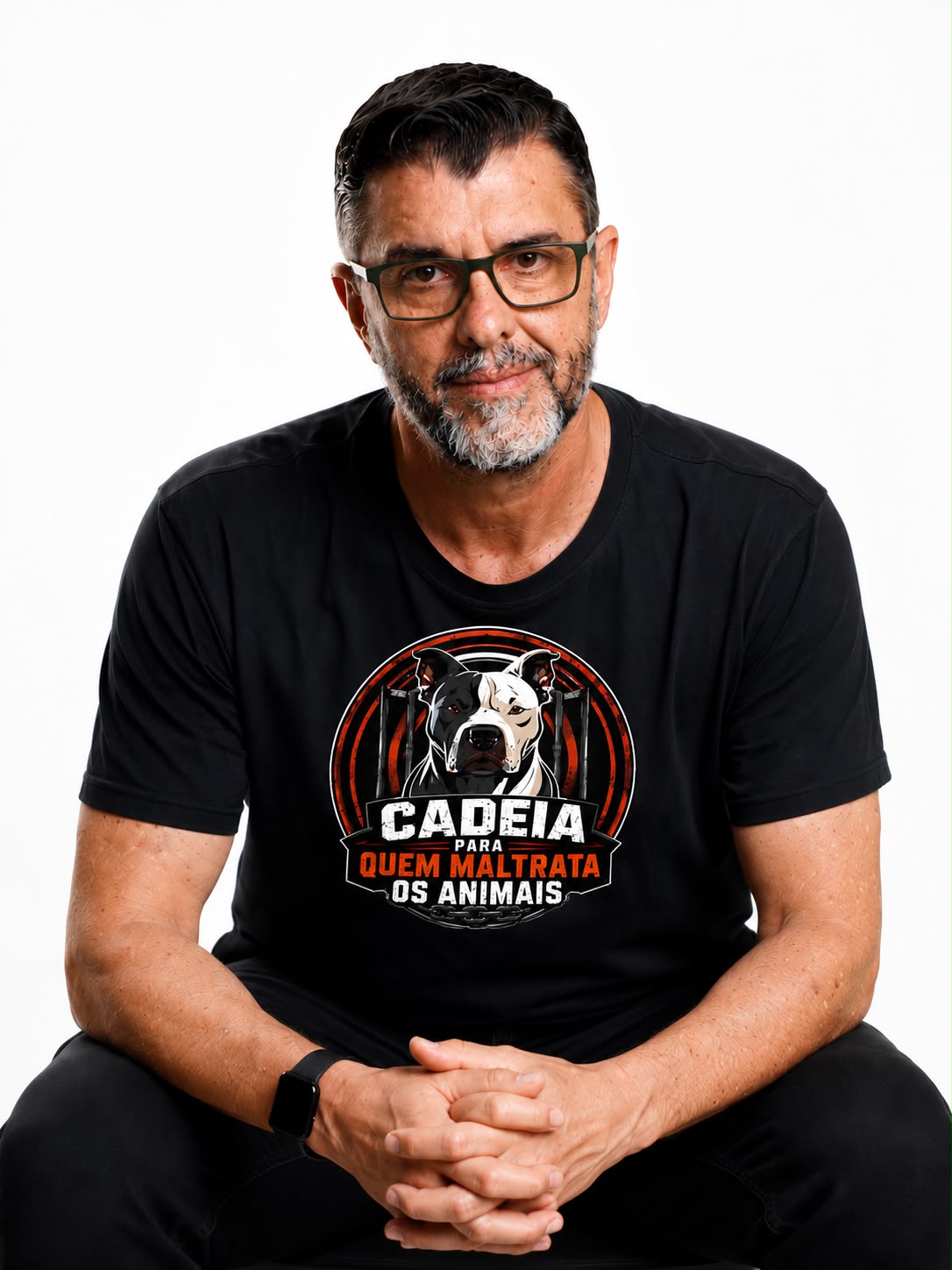 João Valois sentado, mãos unidas, com a camisa do movimento Cadeia para quem maltrata os animais.